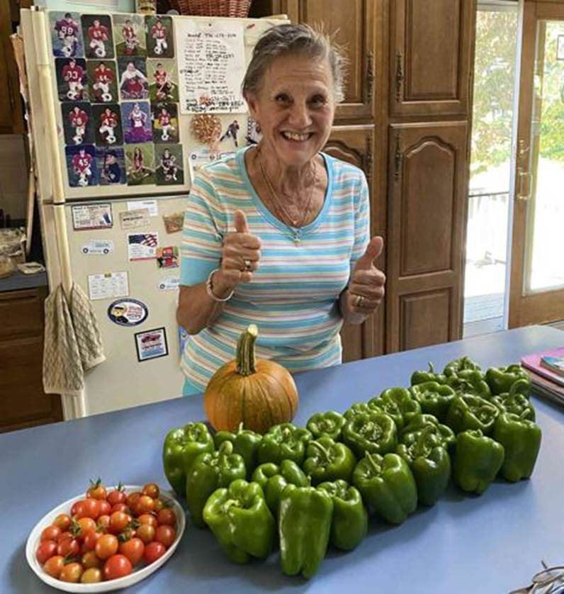 A person giving a thumbs up in front of a table full of vegetables

Description automatically generated