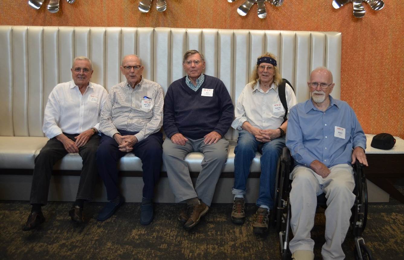 A group of men sitting on a bench

Description automatically generated